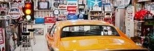 Auto enthusiast shed: Yellow car in garage shed. Walls are covered in auto-themed signs and wall decorations.