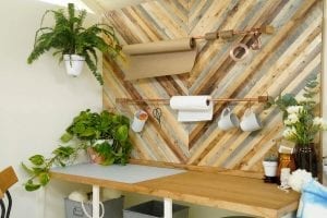 Shed detail: Wooden table top. Plants and rolls of material on wall.