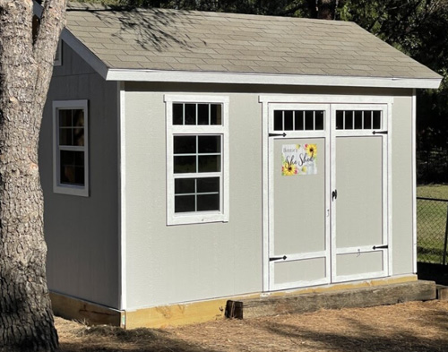 Crafting She Shed: Pastel green shed with sign on door that reads "She Shed."